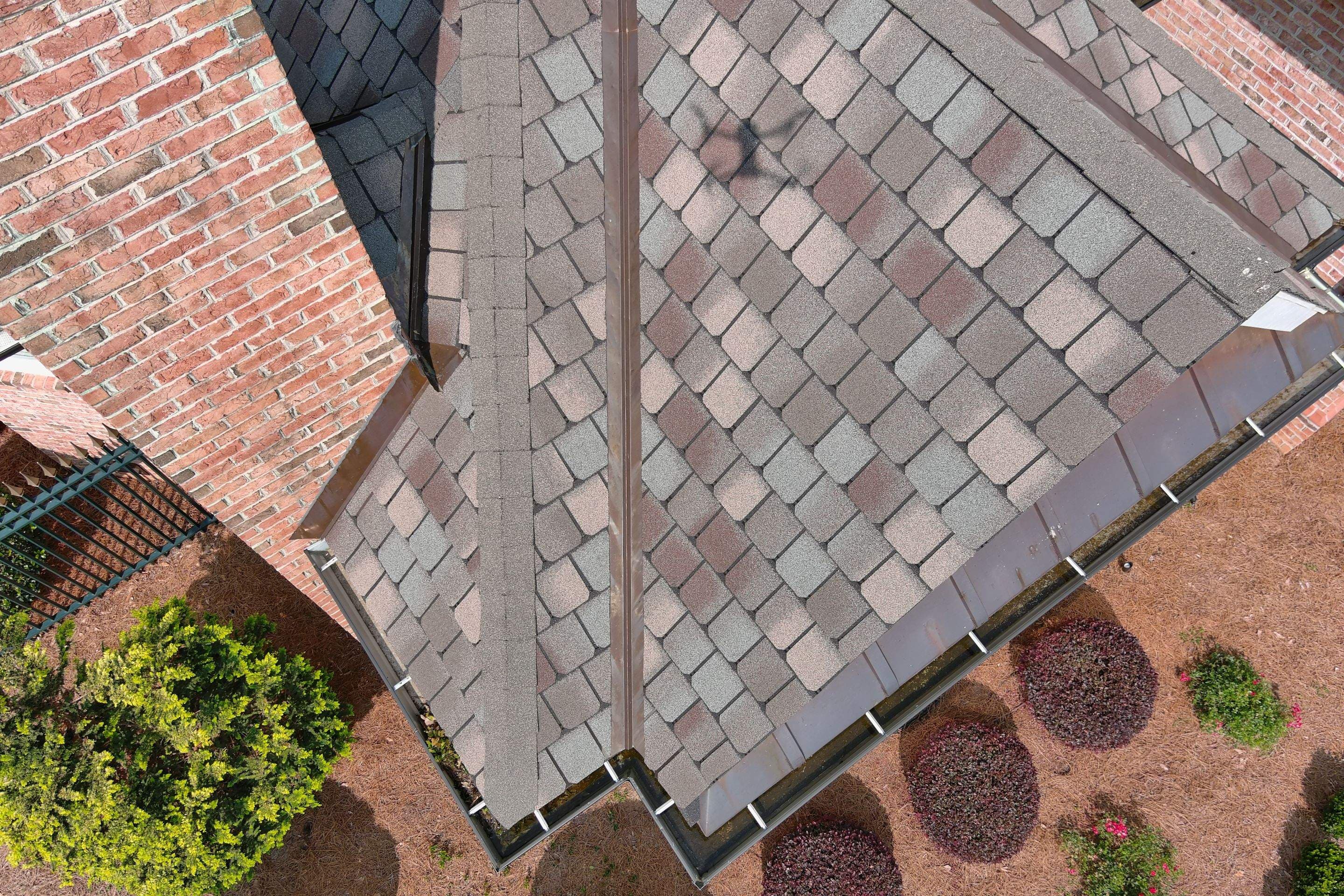 Aerial close-up of a metal roof valley between shingle roof slopes