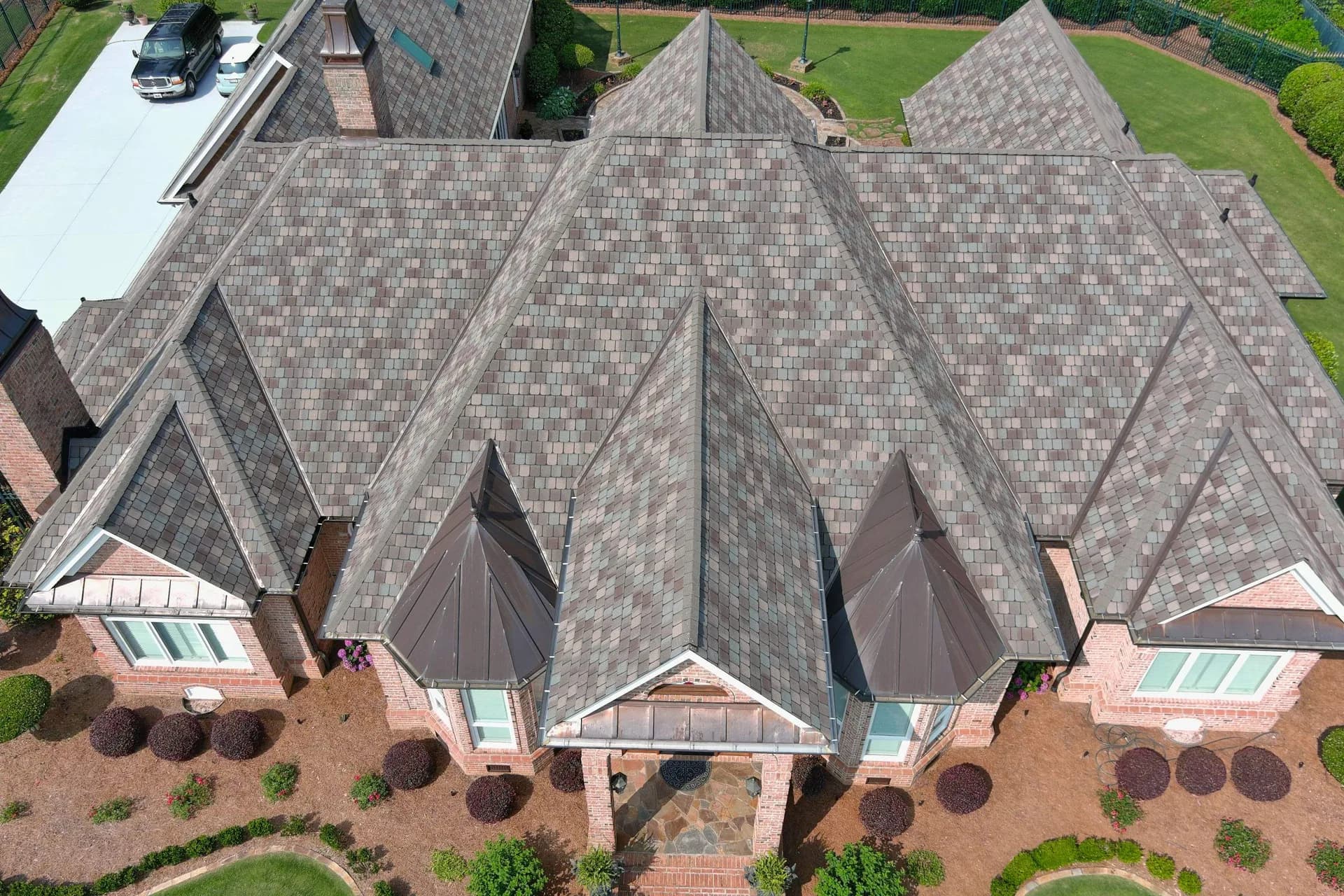 Aerial view of a shingle roof with multiple ridges and copper accents